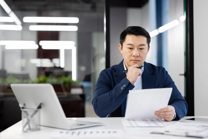 Singapore business owner reviewing financial records while managing daily operations